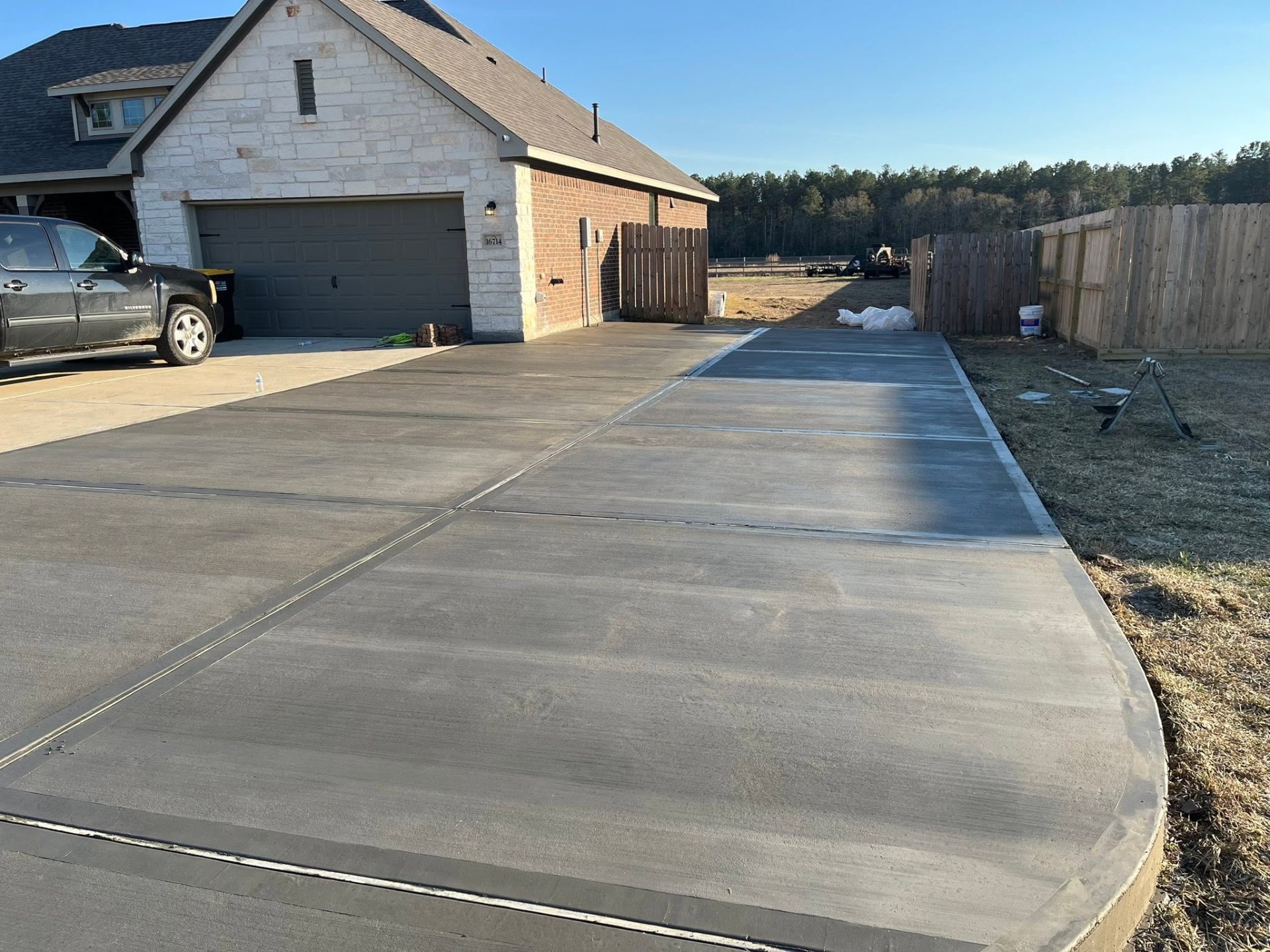 Completed and cured concrete driveway alongside a stone-and-brick home