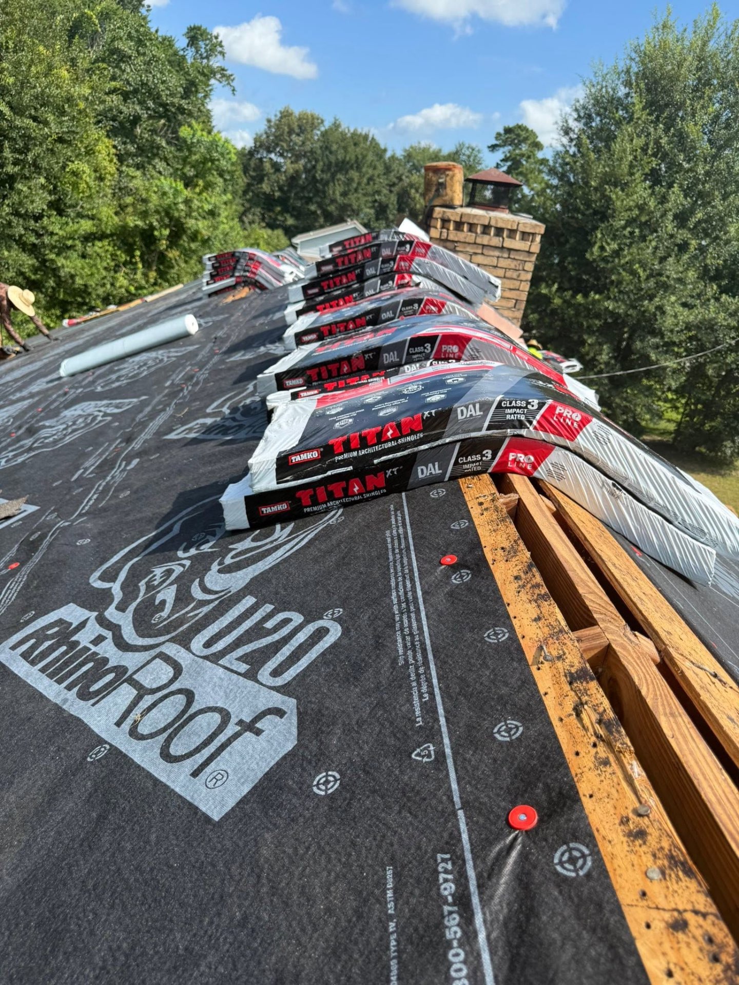 TAMKO Titan XT shingle bundles staged along a ridge over RhinoRoof underlayment