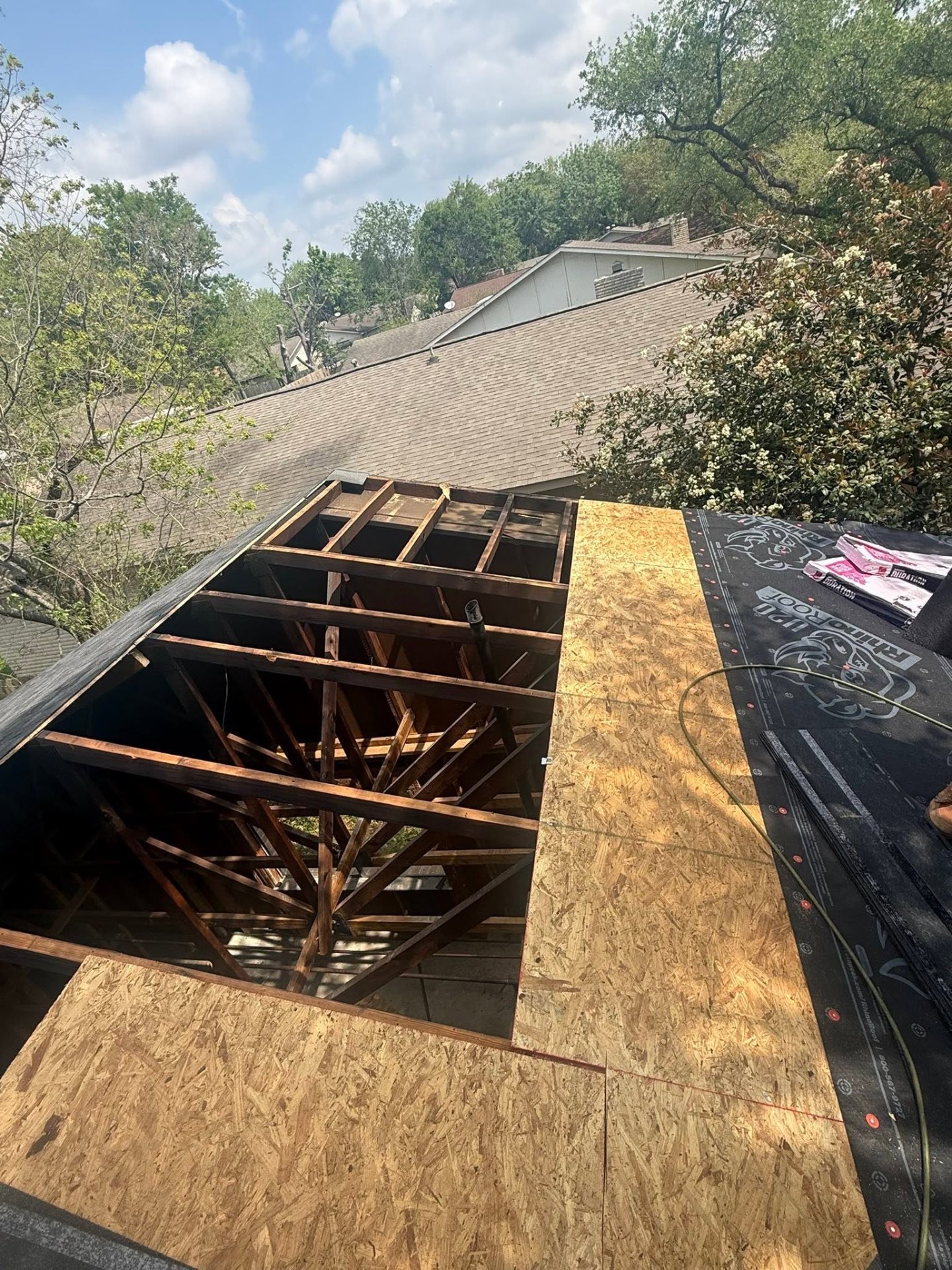 Open roof deck during tear-off showing exposed rafters and fresh OSB decking